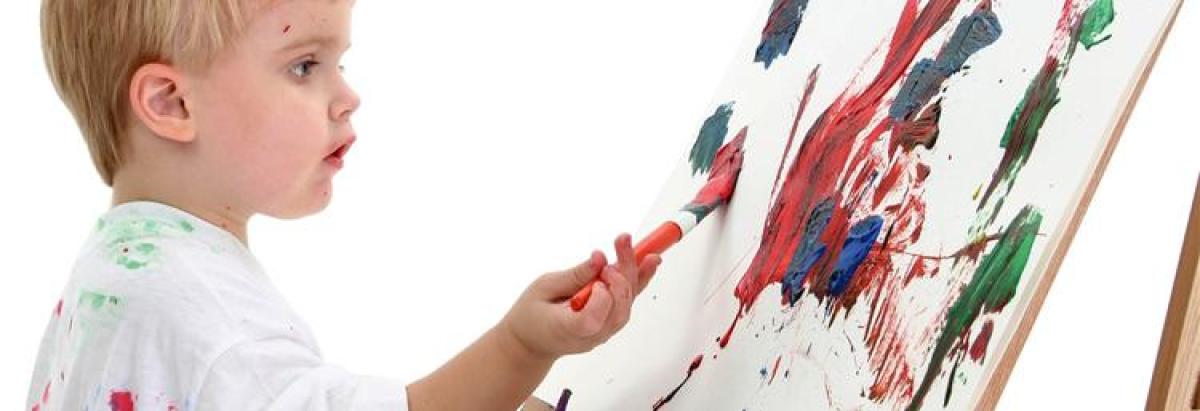 young boy painting on an easel
